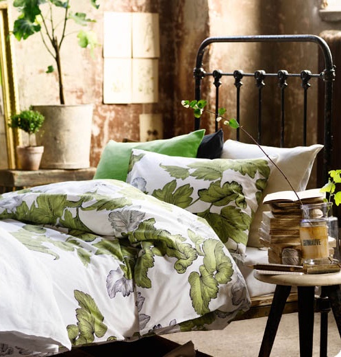 a beautiful spring bedroom with a forged bed, botanical bedding, a stool and some potted greenery is very welcoming