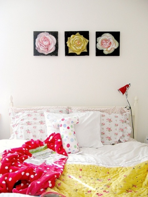 a welcoming and bold spring bedroom with a white bed, colorful bedding, bold floral prints, a red lamp is super cool
