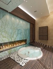 a sunken round bathtub with white pebbles around, with a wooden deck and a built-in fireplace for more relaxation