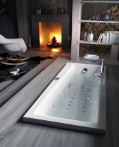 a sunken bathtub with a deck right in the bedroom with a fireplace, looks very natural and very relaxing and enjoyable