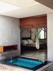 a sunken bathtub with tiles inside and stone around, with shades that separate it from the bedroom