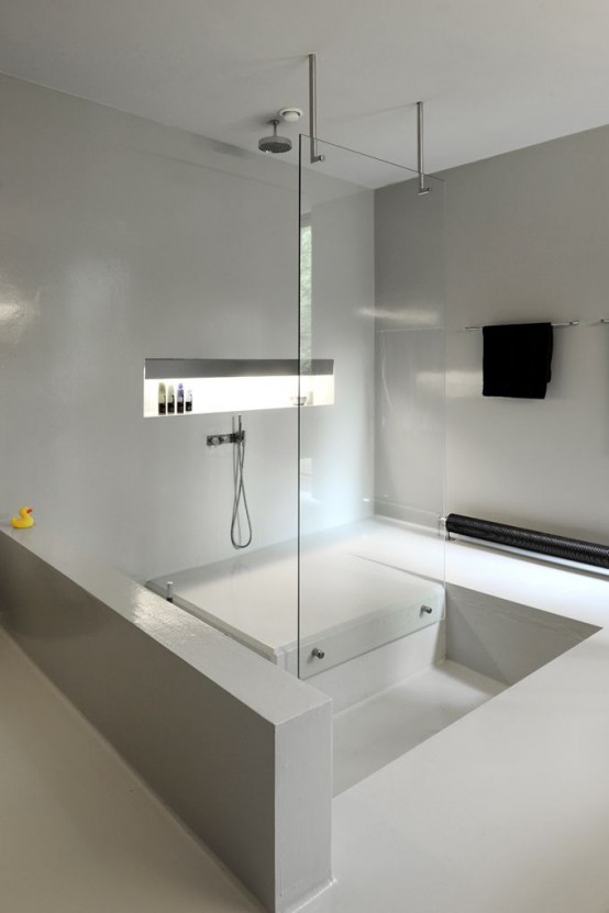 a minimalist white bathroom with a shower space and a sunken bathtub looks all sleek and chic