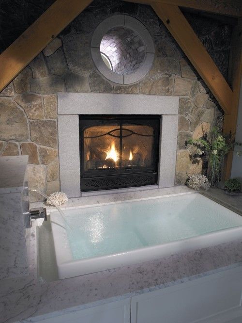 a dreamy soaking sunken bathtub with a fireplace with a waterfall is a very relaxing bathing space