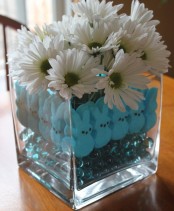 a simple white flower arrangement in a jar with blue beads and blue bunnies for Easter
