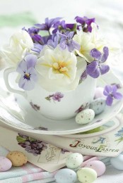 a vintage floral tea pot with some sprign blooms and pastel eggs on the saucer