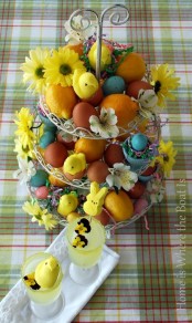 a cupcake stand filled with colorful eggs, blooms and citrus is a bright Easter centerpiece