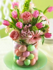 an Easter flower arrangement done in pink and with bright faux eggs in the jar