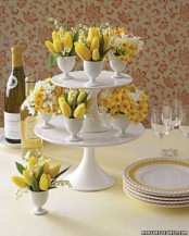 a cupcake stand with egg holders with spring blooms in white and yellow for an Easter centerpiece