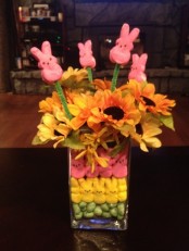 a clear vase filled with colorful bunnies and with bright blooms and bunnies on sticks for Easter