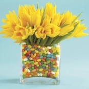 a clear vase with colorful candies and bright yellow tulips for a bold Easter centerpiece