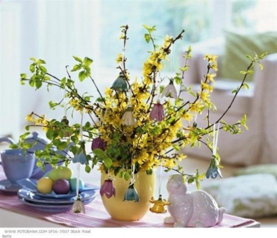 yellow blooming branches and greenery and bells hanging on the branches for a whimsy Easter centerpiece