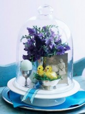 a cute cloche arrangement with a photo, some spring blooms, fake birds and an egg for Easter