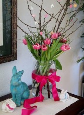 an Easter arrangement with branches and pink tulips plus a matching ribbon
