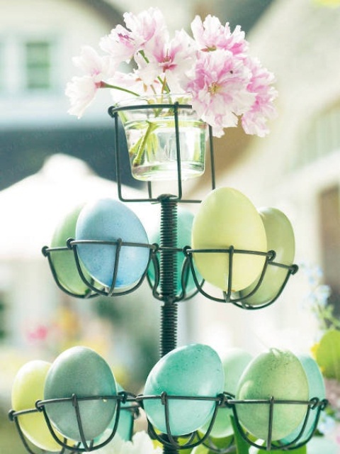 a wire egg holder with lots of cupes and a pink bloom arrangement for Easter