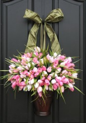 a lush pink and white tulip arrangement in a metal vase with a green bow for Easter front decor