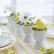 white egg cups with candies, fake chicks and spring blooms for Easter decor