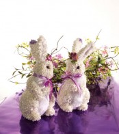 a greenery and pink flower arrangement and a couple of bunnies for an Easter centerpiece