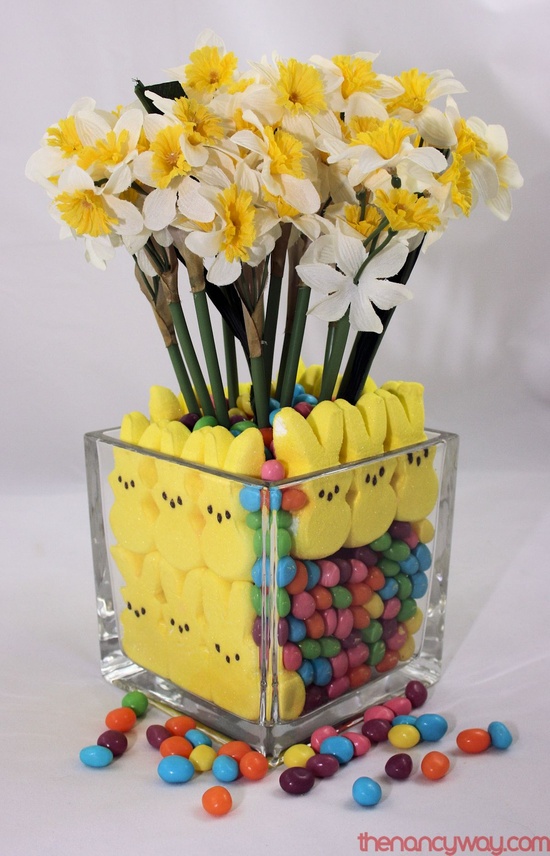 a clear vase with yellow bunnies and candies and yellow daffodils for an Easter centerpiece