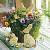 a moss basket with colorful pansies, colorful faux eggs and bunnies