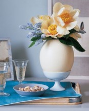a spring flower arrangement placed into an oversized fake egg on a stand for Easter decor
