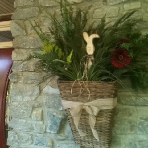 a basket with greenery, blooms, a bow and a bunny can be hung on your porch