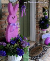 a colorful Easter bunny and oversized egg plus purple blooms in the pots