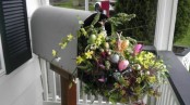 a mail box filled with greenery, bright blooms and branches is a cool porch decoration for Easter