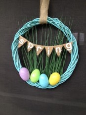 a colorful wire wreath with fake grass, colorful eggs and a bunting