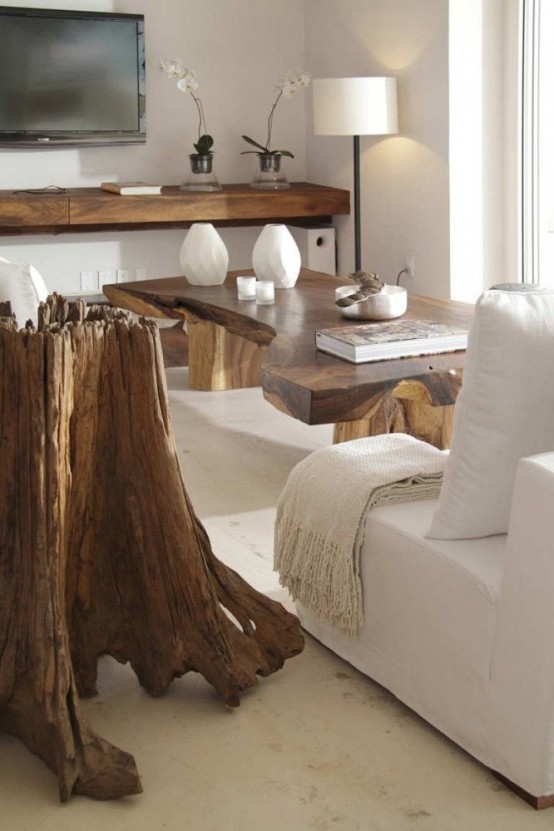 a piece of driftwood as a statement art piece in a modern space, and some staiend wood furniture that echoes with it