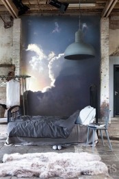 a blackened metal bed with grey bedding is a stylish addition to this industrial bedroom with whitewashed walls and a faux fur rug plus a statement wall