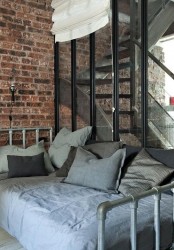 an industrial space with brick walls, a metal bed with grey and blue bedding is a stylish and cool room