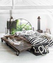 an industrial bed built of pallets, styled with black and white bedding and some stuff by the sleeping zone