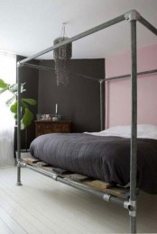 an eclectic bedroom with a pink and a black wall, a blackened metal bed with black and white bedding and a black chandelier