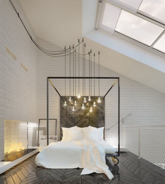 a black and white attic bedroom with a skylight, a fireplace with lights, a metal bed on casters with white bedding and a cluster of bulbs