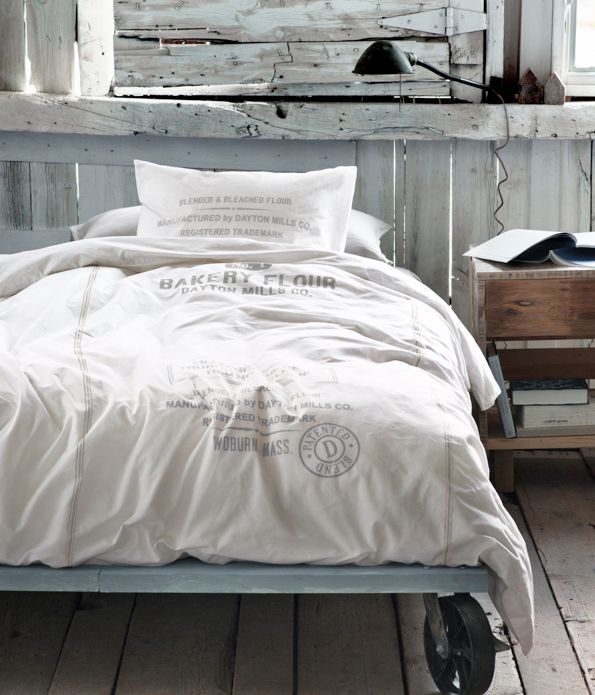 a metal industrial bed on casters with white bedding is a proper addition to this wabi sabi meets industrial bedroom