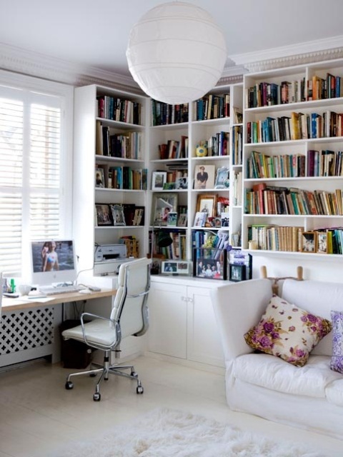 a white feminine home office with open storage units, a white desk and sofa and floral pillows looks chic and cool