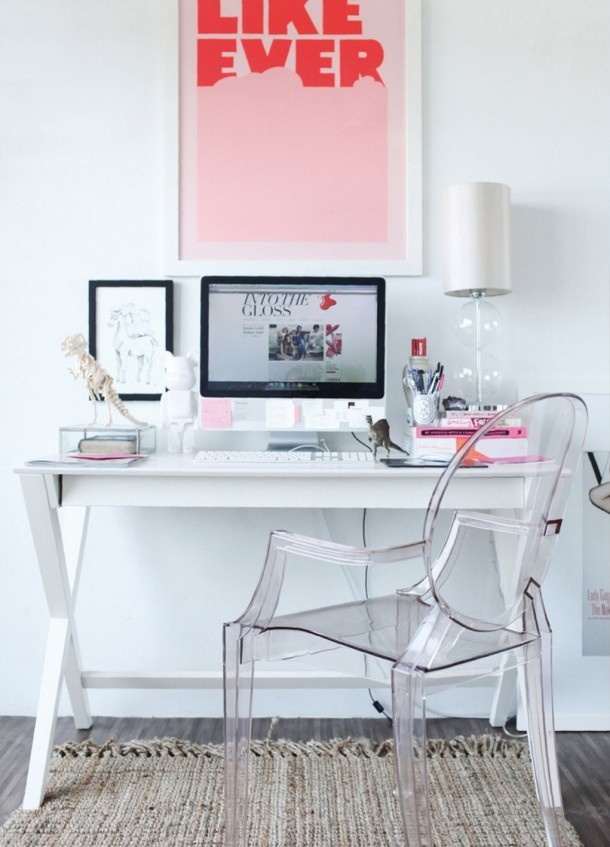 a modern feminine home office with a white desk, an acrylic chair, a bright poster and bright pink touches