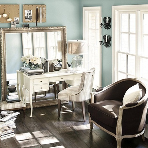 a refined powder blue home office with a statement mirror, a white desk, a brown sofa and touches of elegant decor