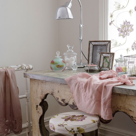 a refined shabby chic home office with neutral walls, a carved desk, a floral curtain and neutral silk textiles