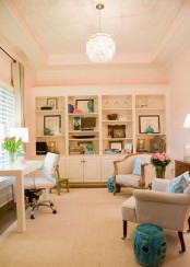 an elegant blush home office with a large storage unit that takes a whole wall, more neutral furniture and a crystal chandelier plus touches of blue