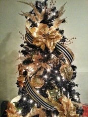 a gold and black Christmas tree with striped ribbons, shiny touches and ornaments, lights and twigs is lovely and cool