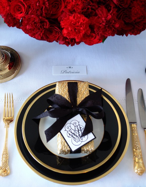 a super elegant and refined Christmas or NYE table with black and gold porcelain, cutlery and a gift box plus red roses is wow