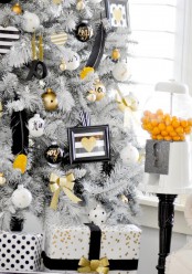 a white Christmas tree with black, white and gold ornaments, with signs, calligraphy and feathers is a lovely glam idea for winter holidays