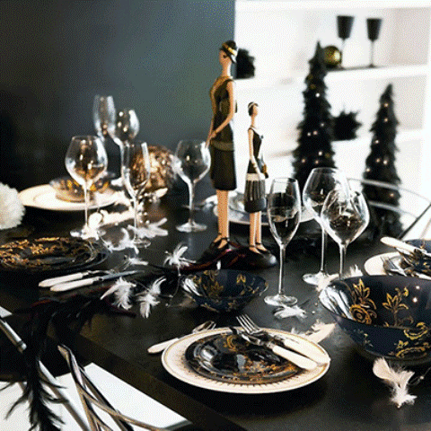 a black and gold Christmas tablescape with elegant patterned bowls and plates, feathers, dolls and neutral cutlery is very chic