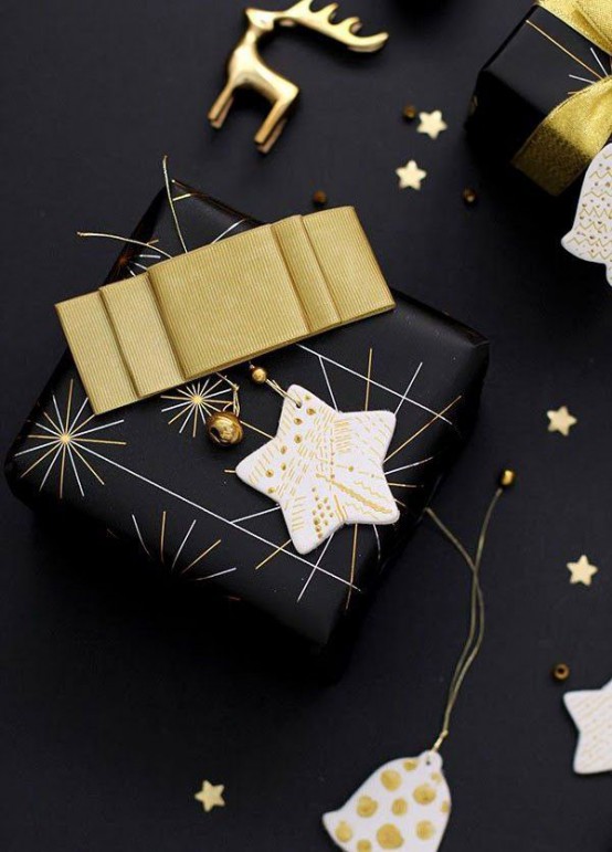 a black Christmas gift wrapped with a gold bow, a clay star ornament and smaller gold ones is lovely and very chic