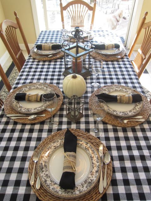 a rustic black and white Thanksgiving tablescape with a checked tablecloth, black napkins, patterned plates and woven placemats is amazing