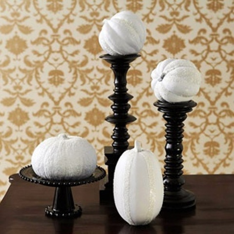 a simple black and white Thanksgiving decoration of black wooden stands and white pumpkins on them is a stylish solution