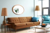 a rust-colored mid-century modern sofa, matching lamps, a blue chair and a blue pillow, a coffee table, a round mirror