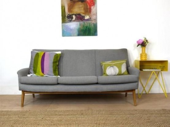 a grey mid-century modern sofa, bright pillows, a side table and a bright artwork are a nice combo for a mid-century modern living room