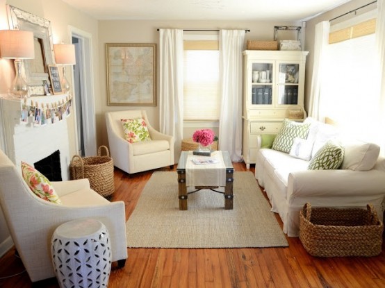 a sweet small farmhouse living room done in neutrals, with a fireplace and comfy furniture, a bookcase and artworks